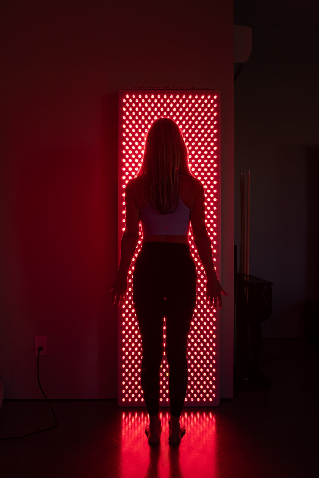 Mito Red Light panel array — deep red photobiomodulation glow in a dark wellness room